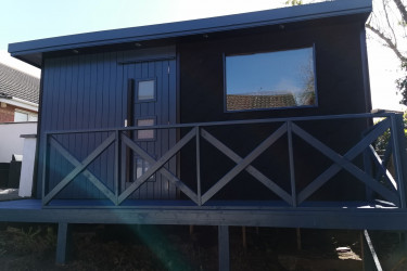 An image of a very nice raised dark blue shed with balcony and scale patterns.