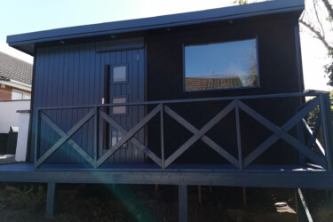 An image of a very nice raised dark blue shed with balcony and scale patterns.