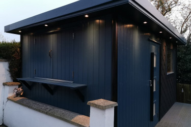 An image of a very nice raised dark blue shed with balcony and scale patterns.