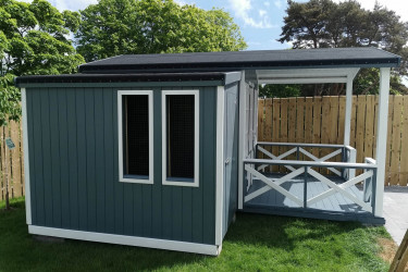 An image of a blue grey garden shed with a patio and French doors.